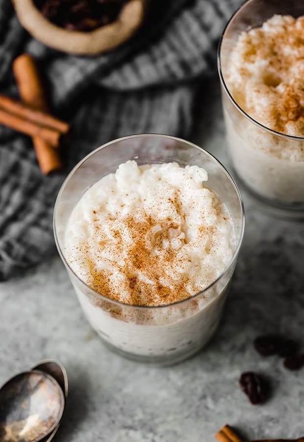 A glass cup full of Mexican Rice Pudding (Arroz con Leche) with a sprinkle of ground cinnamon over top.