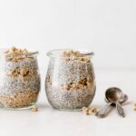 Chia pudding in a jar that's layered with granola, against a white background.