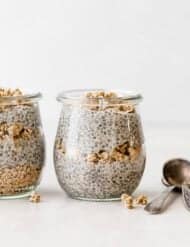 Chia pudding in a jar that's layered with granola, against a white background.