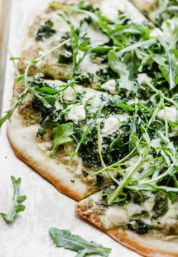 A close up of a kale pizza topped with fresh arugula.