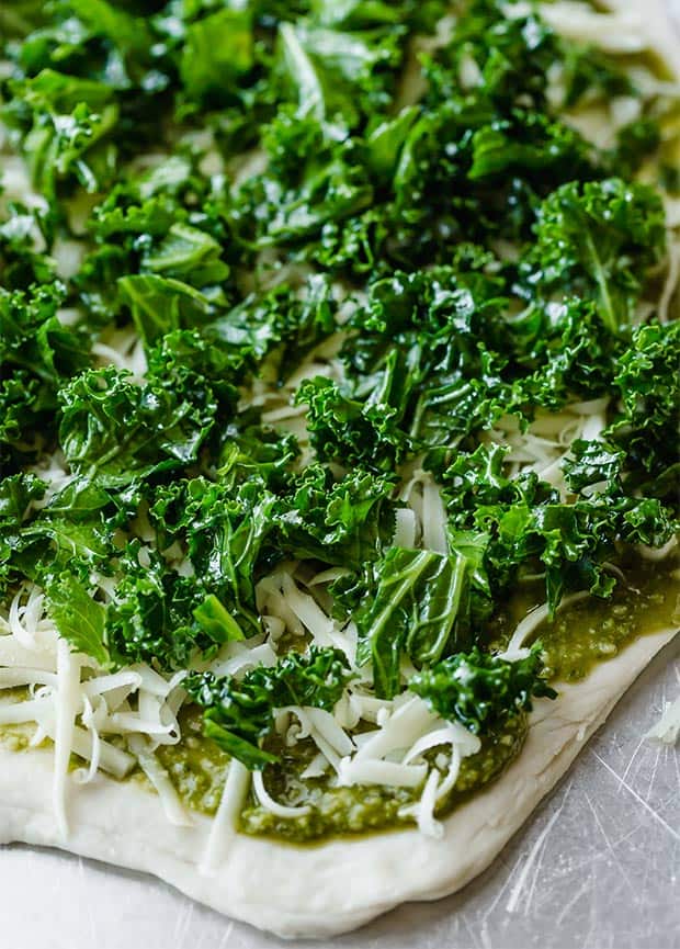 Freshly chopped kale over top of a pizza dough crust, pesto, and mozzarella.