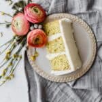 A slice of lemon poppy seed layer cake on a tan plate.