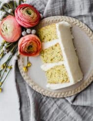 A slice of lemon poppy seed layer cake on a tan plate.