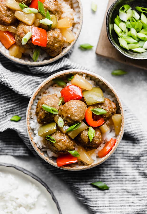 A bowl of Sweet and Sour Meatballs Recipe topped with chopped green onions.