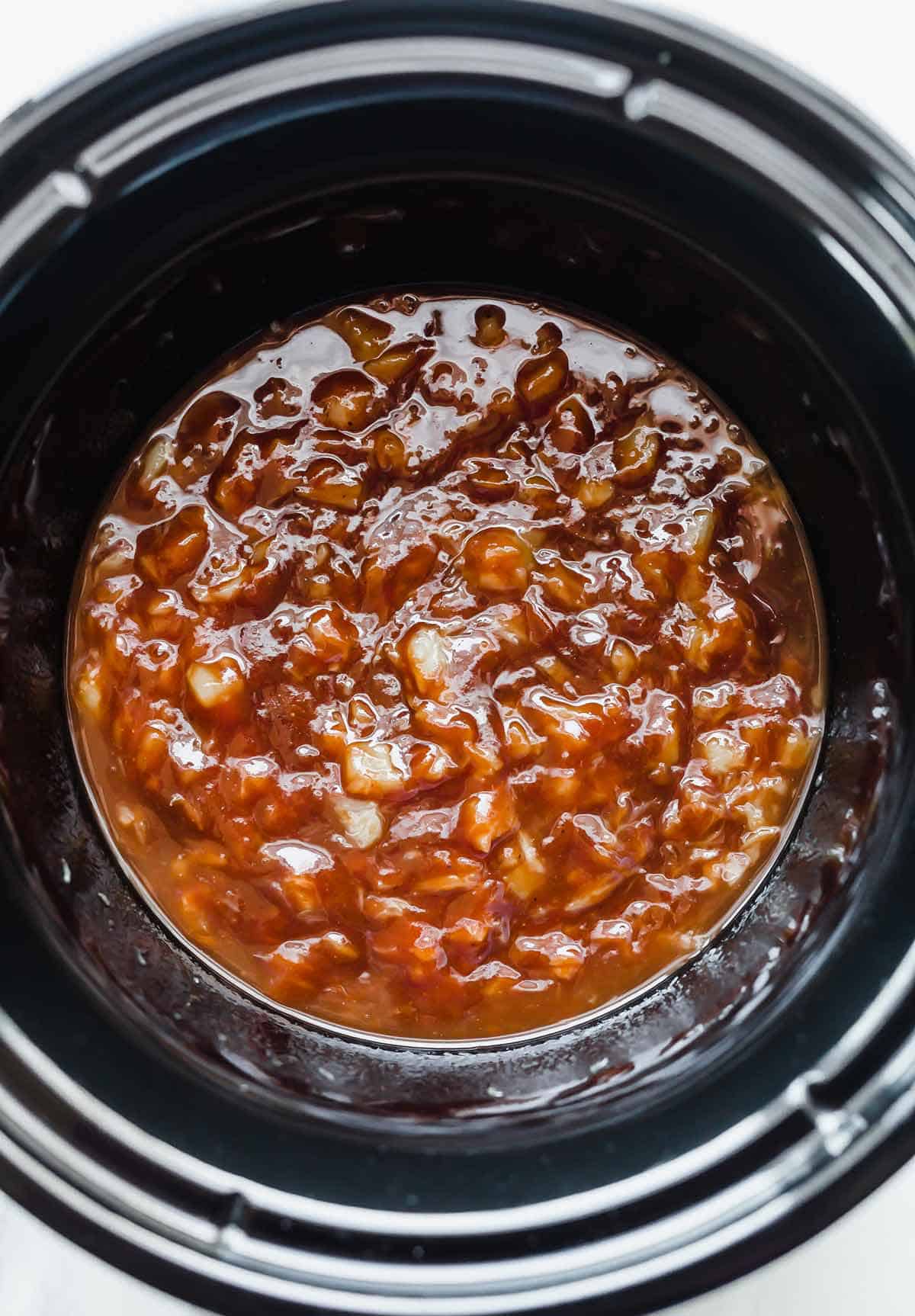 BBQ sauce and crushed pineapple in a black round crockpot.