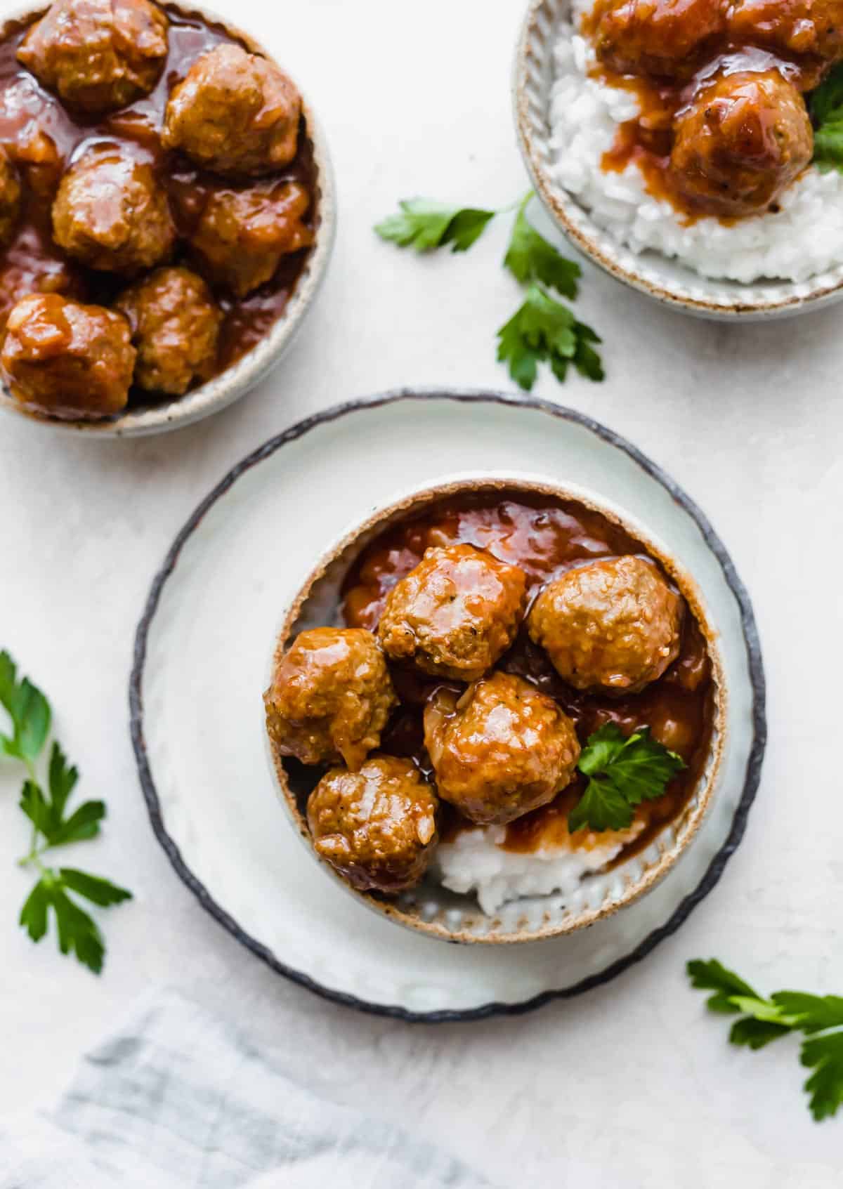 A bowl filled with rice, and BBQ Pineapple Meatballs on a white background.