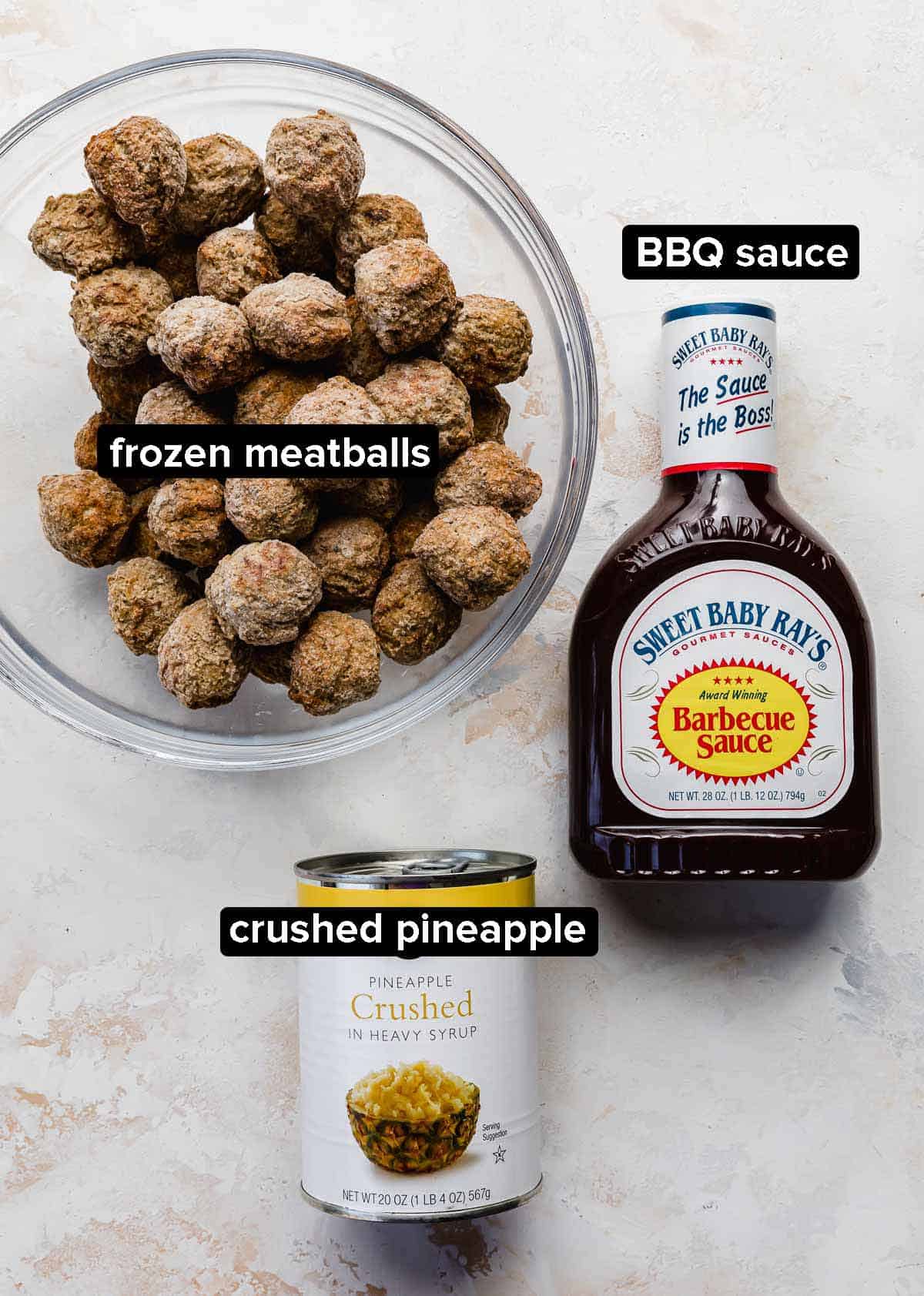 BBQ Pineapple Meatballs ingredients: frozen meatballs, Sweet Baby Rays BBQ sauce bottle, and can of crushed pineapple on a white background.