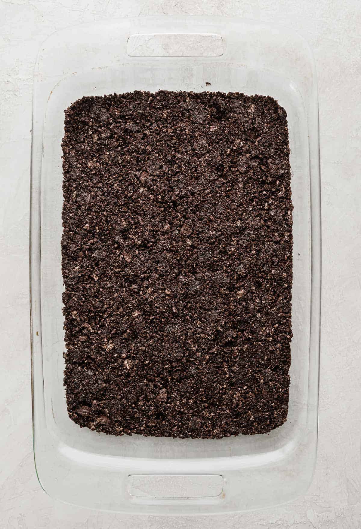 Crushed oreo crust covering the bottom of a rectangular baking dish.