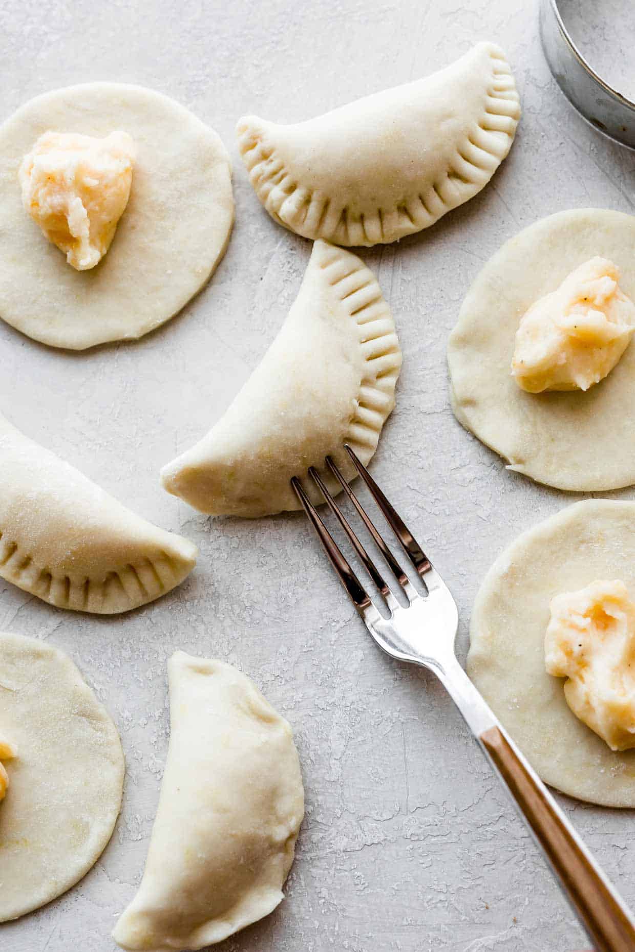 Pierogie dough made with sour cream, shaped into pierogies with a forks tines pressing into the outside edges.