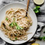 A white plate with a helping of lemon pasta on it, garnished with fresh parsley.