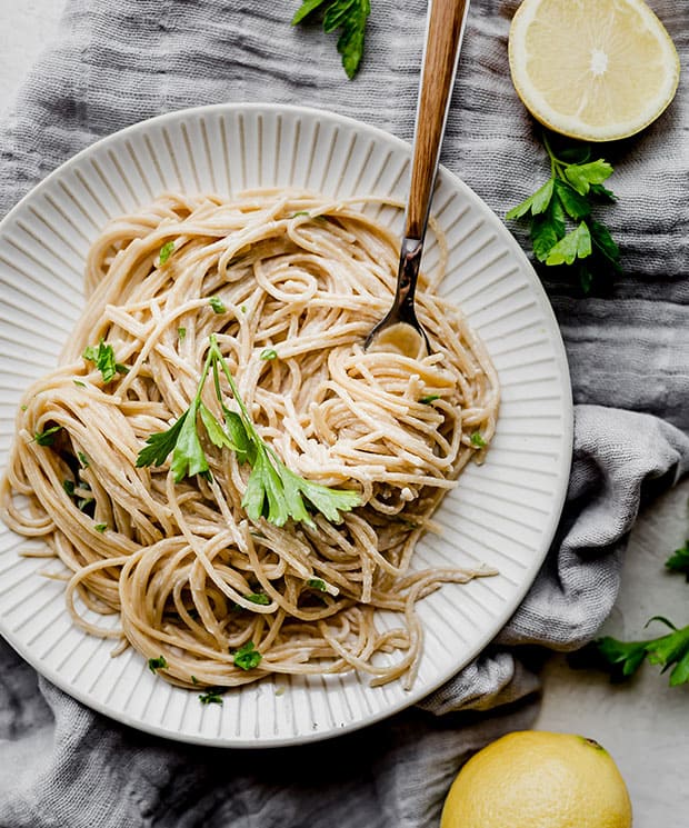 A white plate with a helping of lemon pasta on it, garnished with fresh parsley.