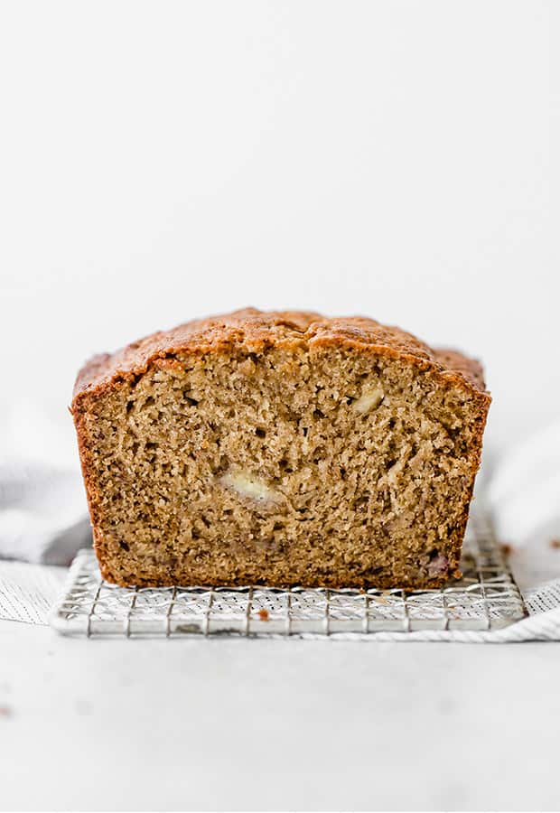 A moist banana bread loaf sitting on a small wire rack. 