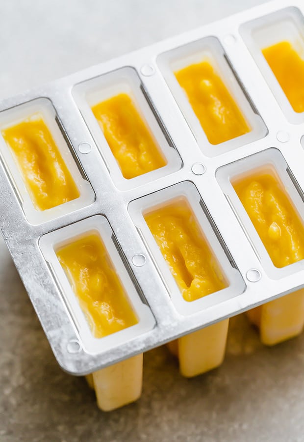 Popsicles molds full of pineapple mango puree.