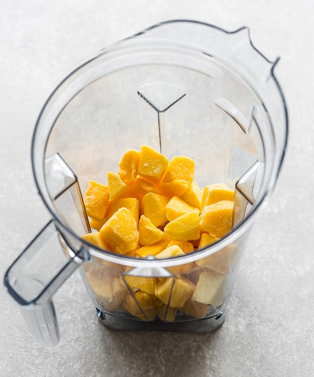 A blender full of frozen mango chunks.