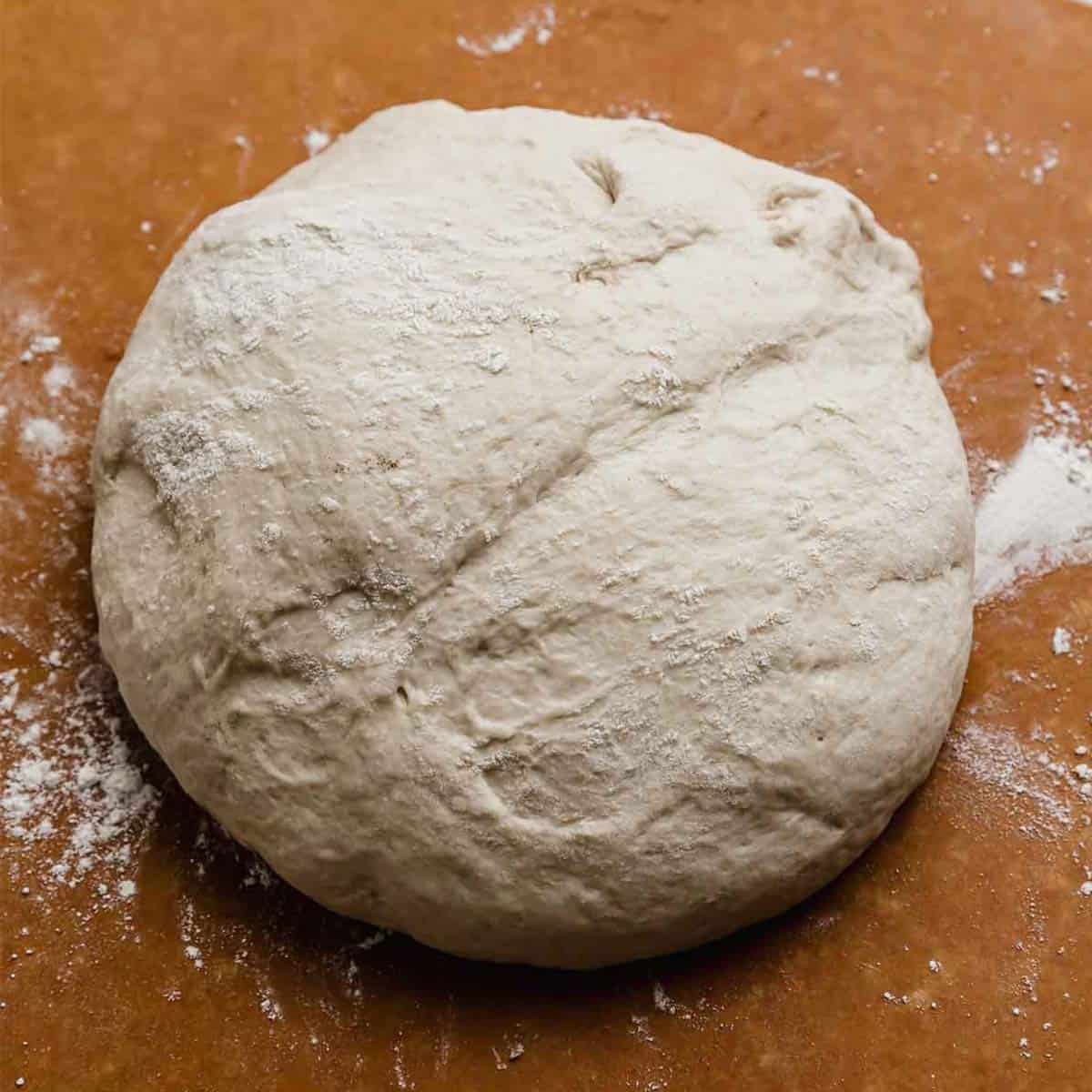a ball of Pizza Dough on a brown background.