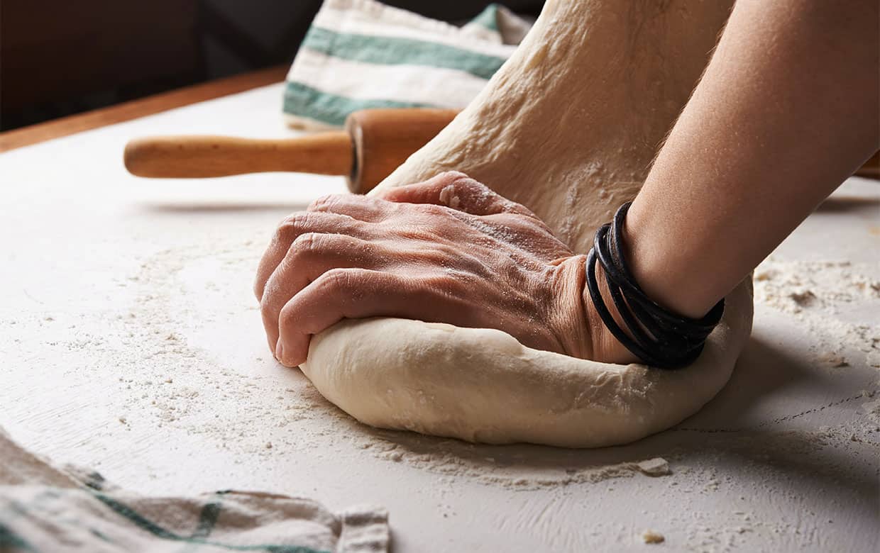 Baker using a wooden spoon to stir dough in mixing bowl stock