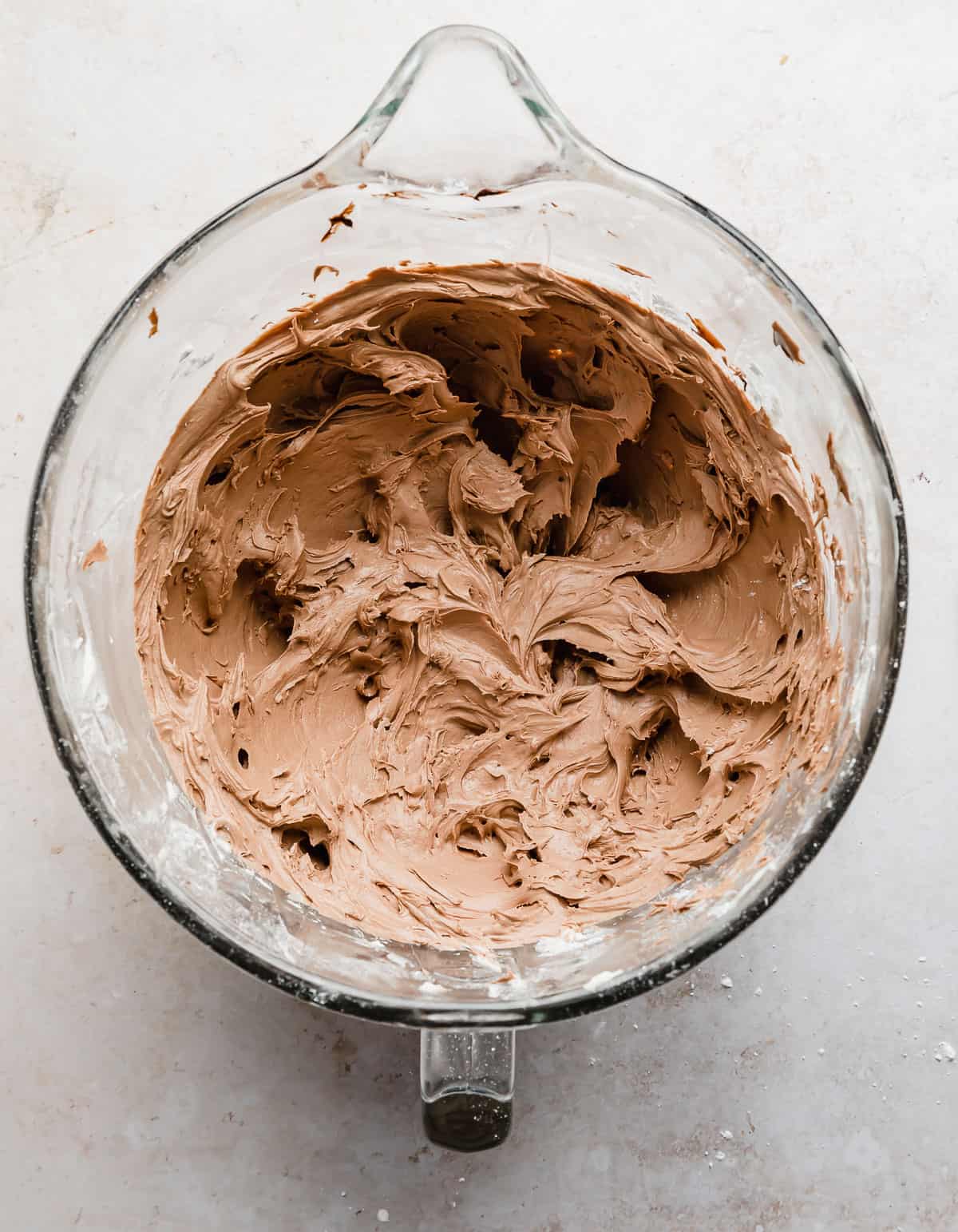 Chocolate Buttercream Frosting made with Melted Chocolate in a glass bowl on a white background.