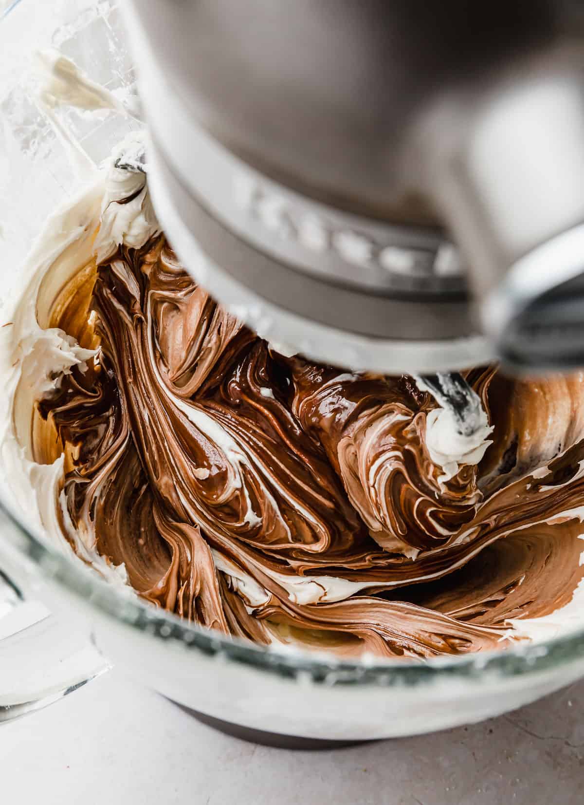Chocolate Buttercream Frosting with Melted Chocolate in a glass bowl of a stand mixer.