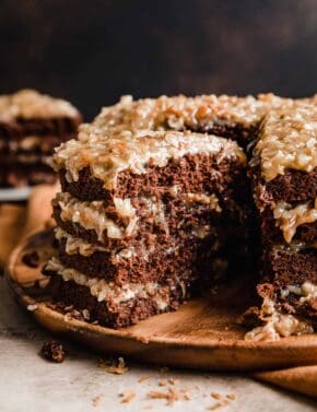 A four layer A traditional German Chocolate Cake recipe with a slice cut from the main cake.