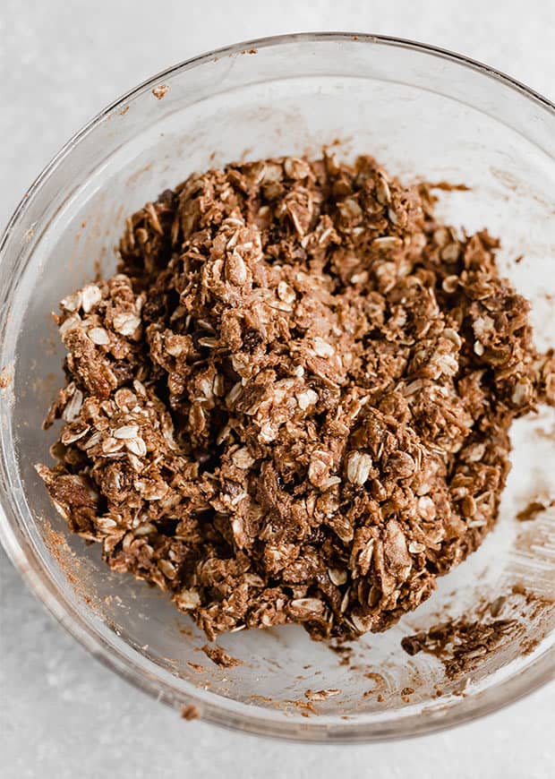 Ingredients to make healthy almond joy energy bites in a glass bowl, all mixed together. 