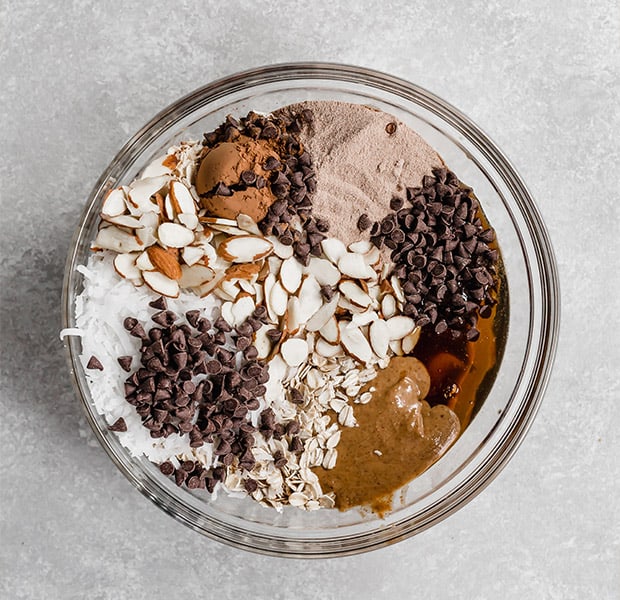 A glass bowl full of the ingredients to make healthy almond joy energy bites