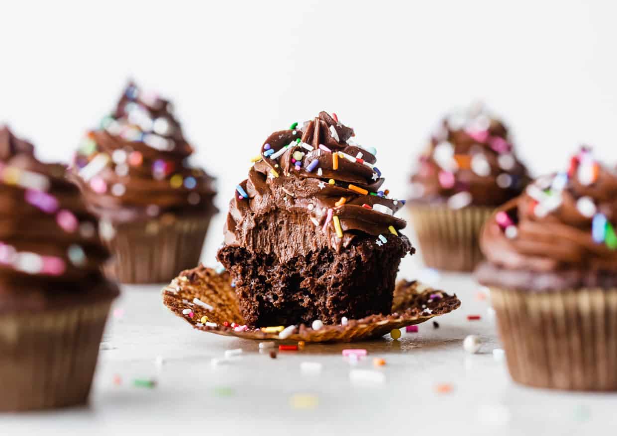 The Best Chocolate Cupcakes topped with chocolate buttercream and colorful sprinkles on a white background.