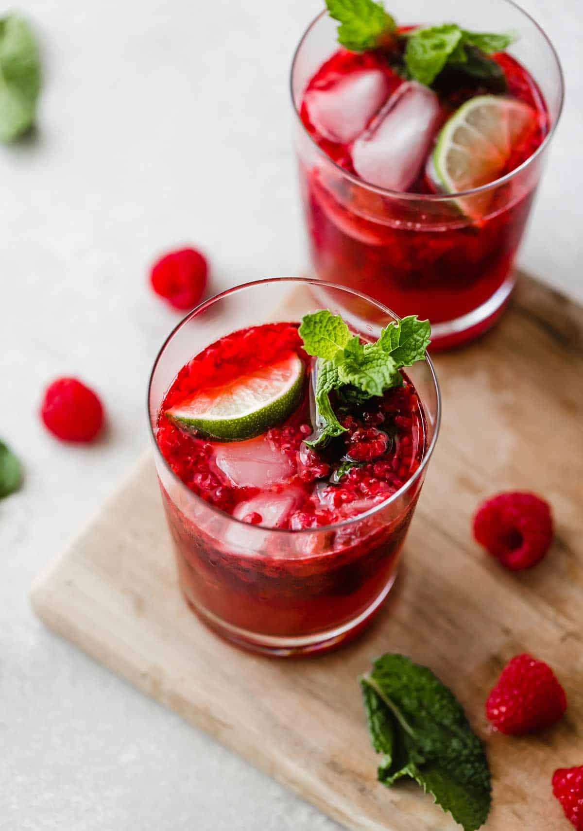 A cup of Raspberry Mojito Mocktail with fresh mint and lime wedge in the drink.