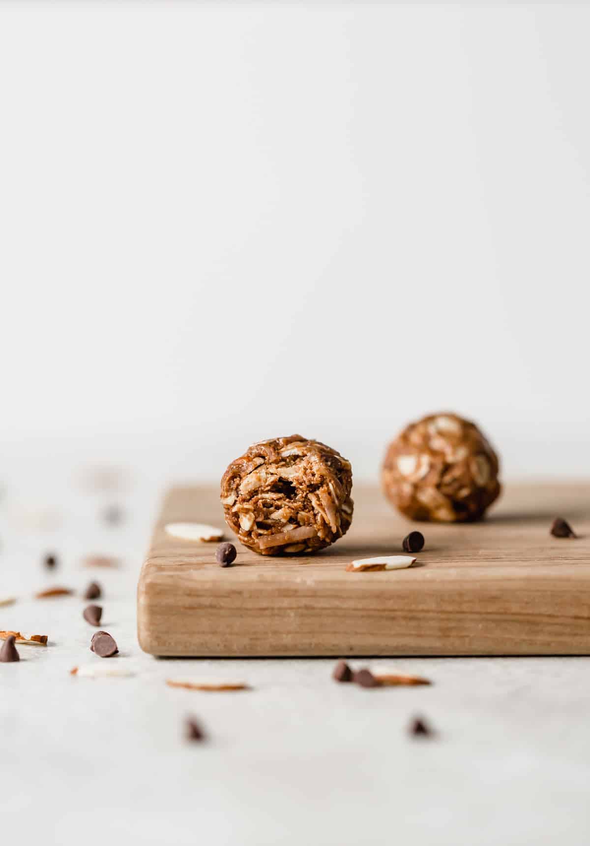 An Almond Joy Protein Ball on a wood cutting board with a bite taken out of it. 