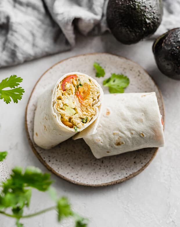 A Avocado Chicken Wrap cut in half, on a plate.