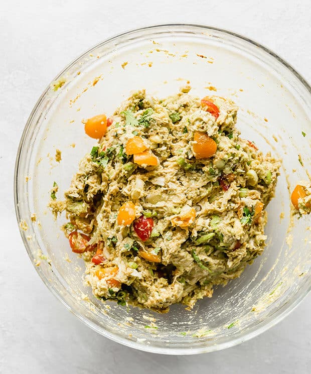 A bowl with Avocado Chicken Wraps ingredients: chicken, avocado, tomatoes, and spices.