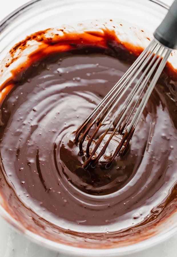 A whisk in a bowl full of chocolate ganache.