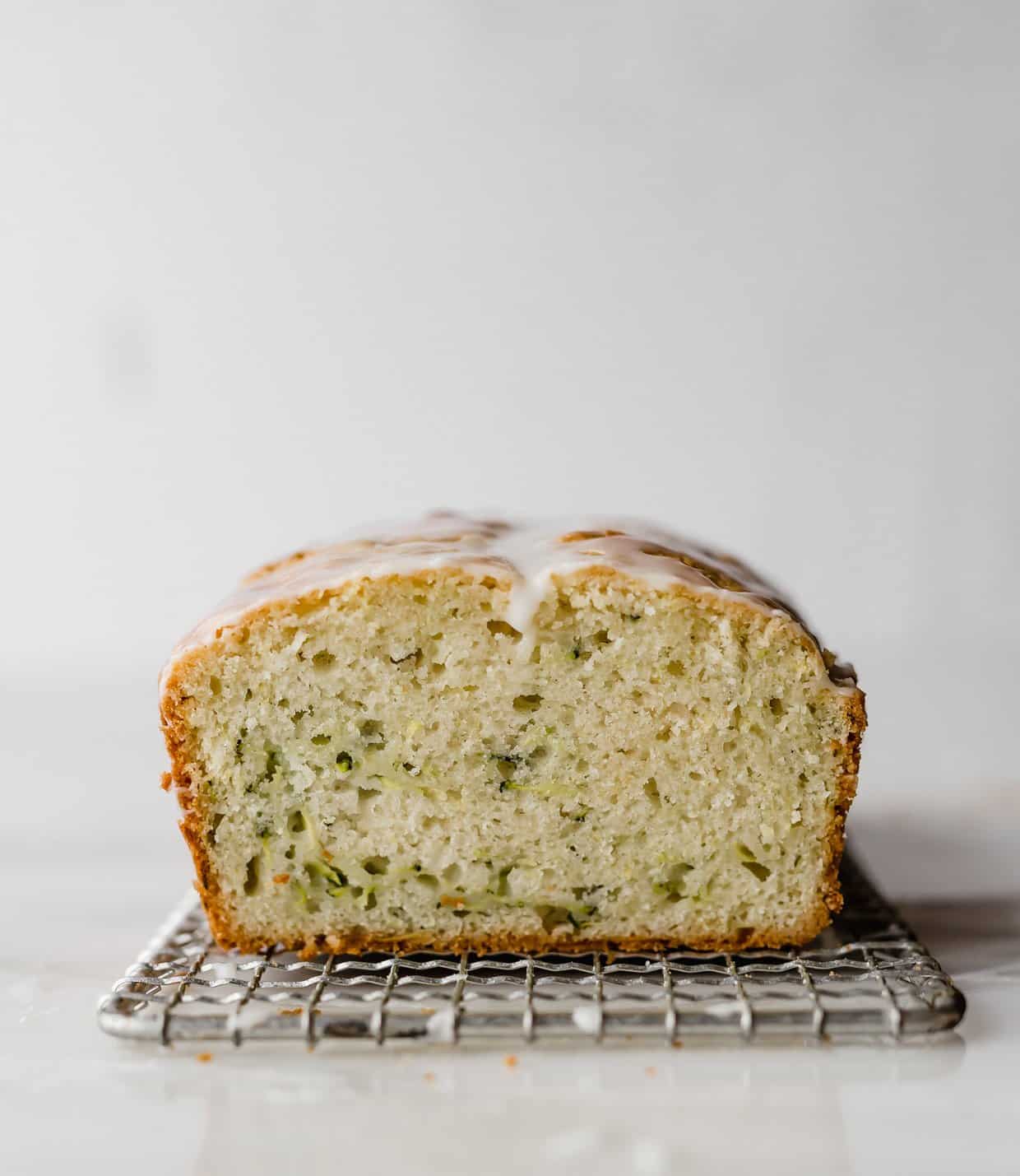 A sliced Lemon Zucchini loaf on a wire rack against a white background.