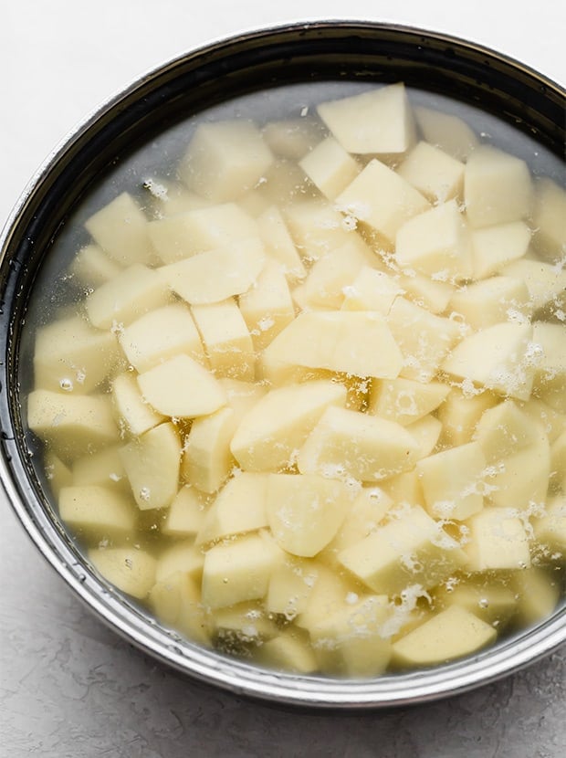 A large pot of cold water and chopped Yukon gold potatoes, for making mashed potatoes.