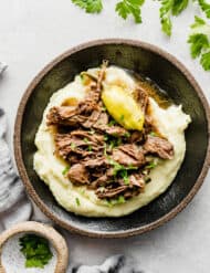 Mississippi Pot Roast on a bed of mashed potatoes with a garnish of parsley.