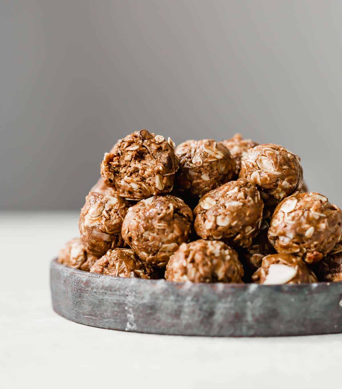 Almond Joy Protein Balls stacked on a black plate.