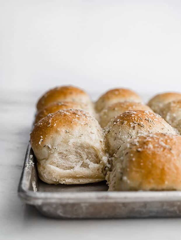 A side photograph of a fluffy Rosemary dinner roll.