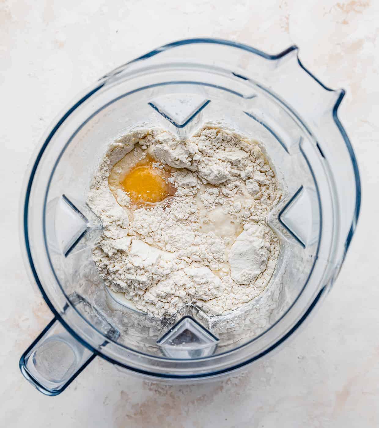 A blender with flour, eggs, and milk in it.