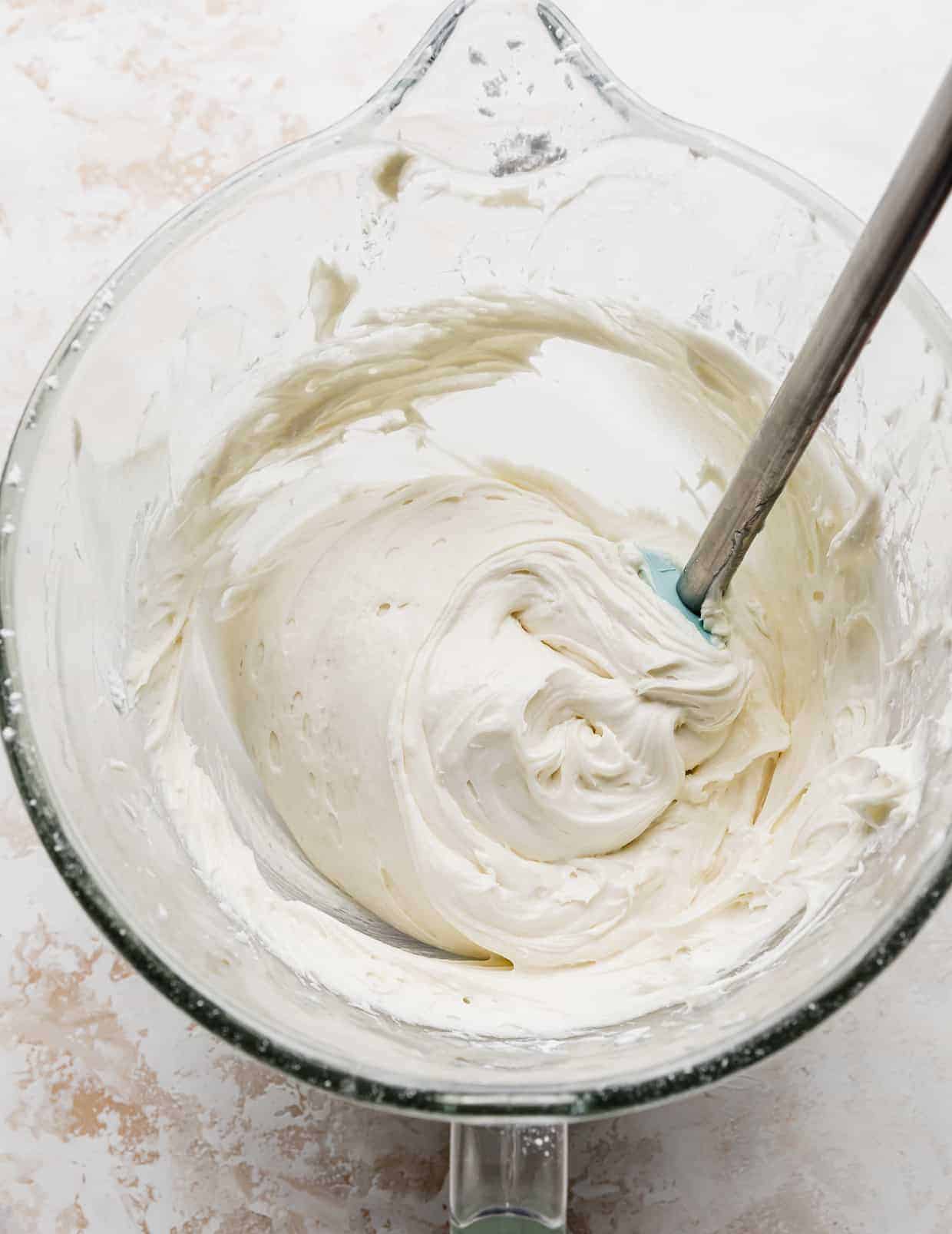 Vanilla cake frosting in a glass mixing bowl.