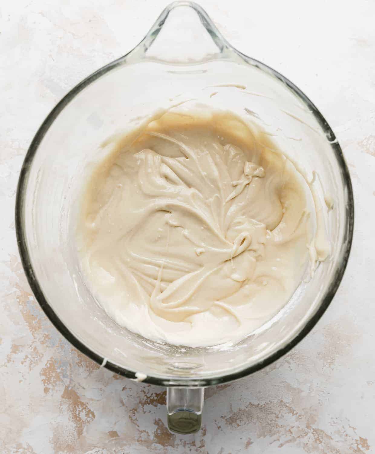 An off-white colored Smash Cake Recipe cake batter in a glass mixing bowl.