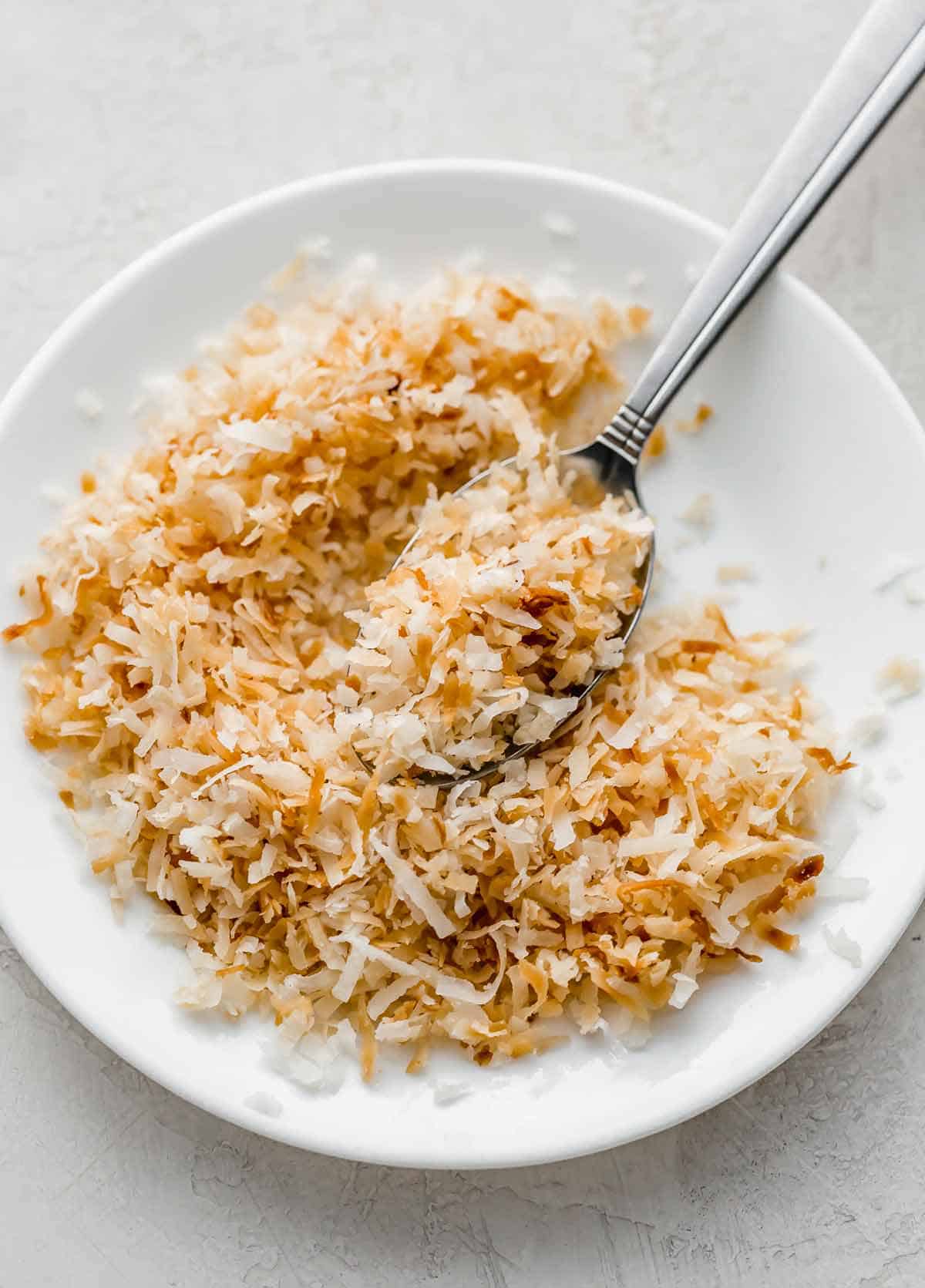 Golden toasted coconut on a white plate.