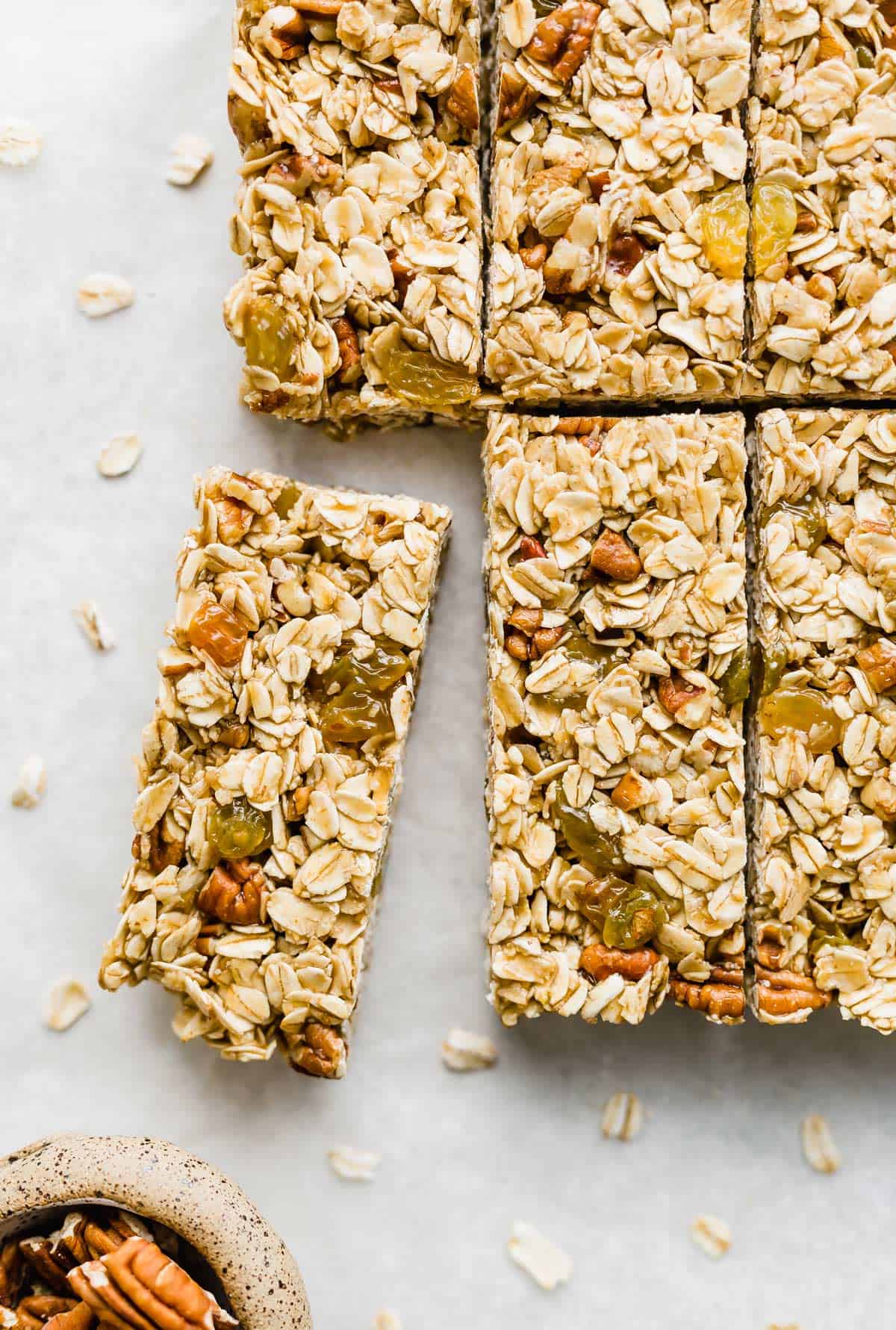 Homemade granola bars filled with rolled oats, nuts, and golden raisins, cut into bars on a white background.