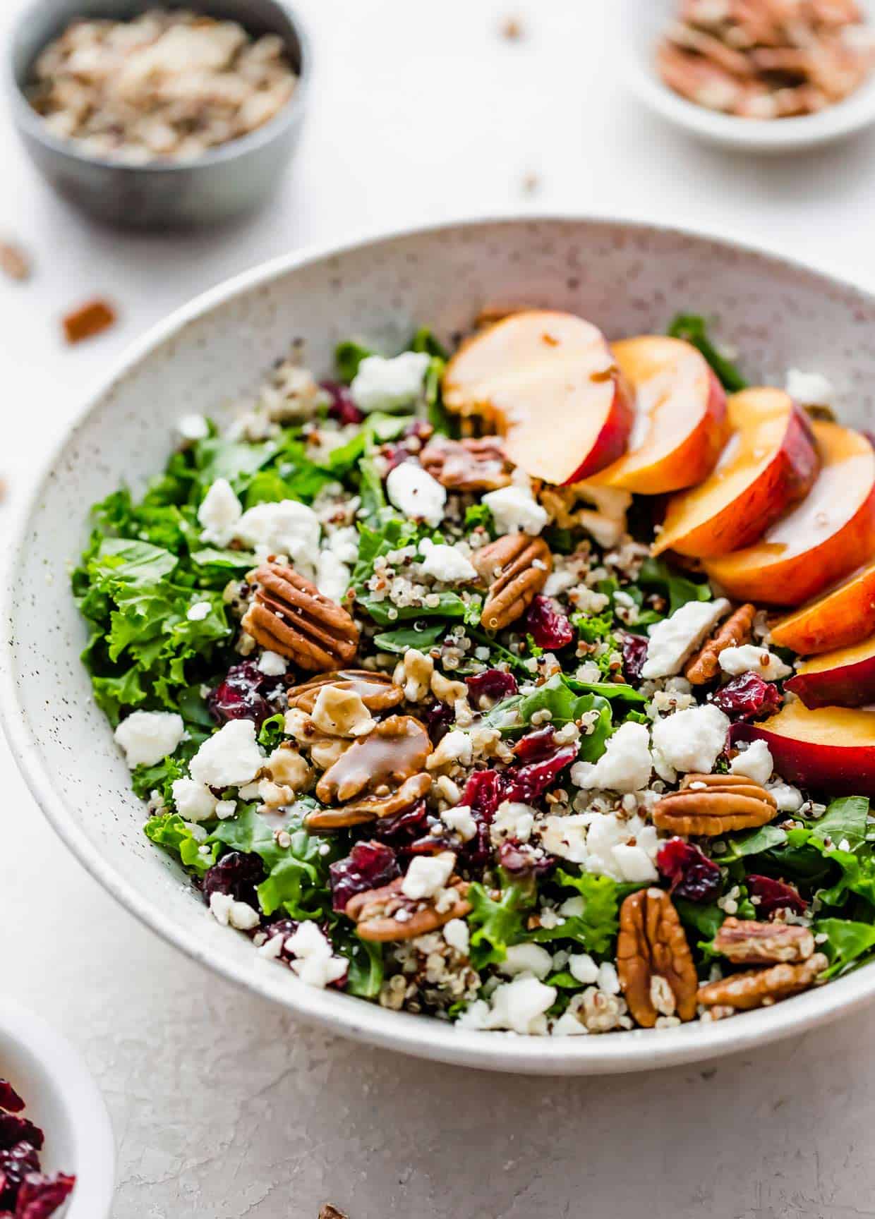 Kale and Quinoa Salad with Craisins and Feta and a sliced peach in a white bowl.
