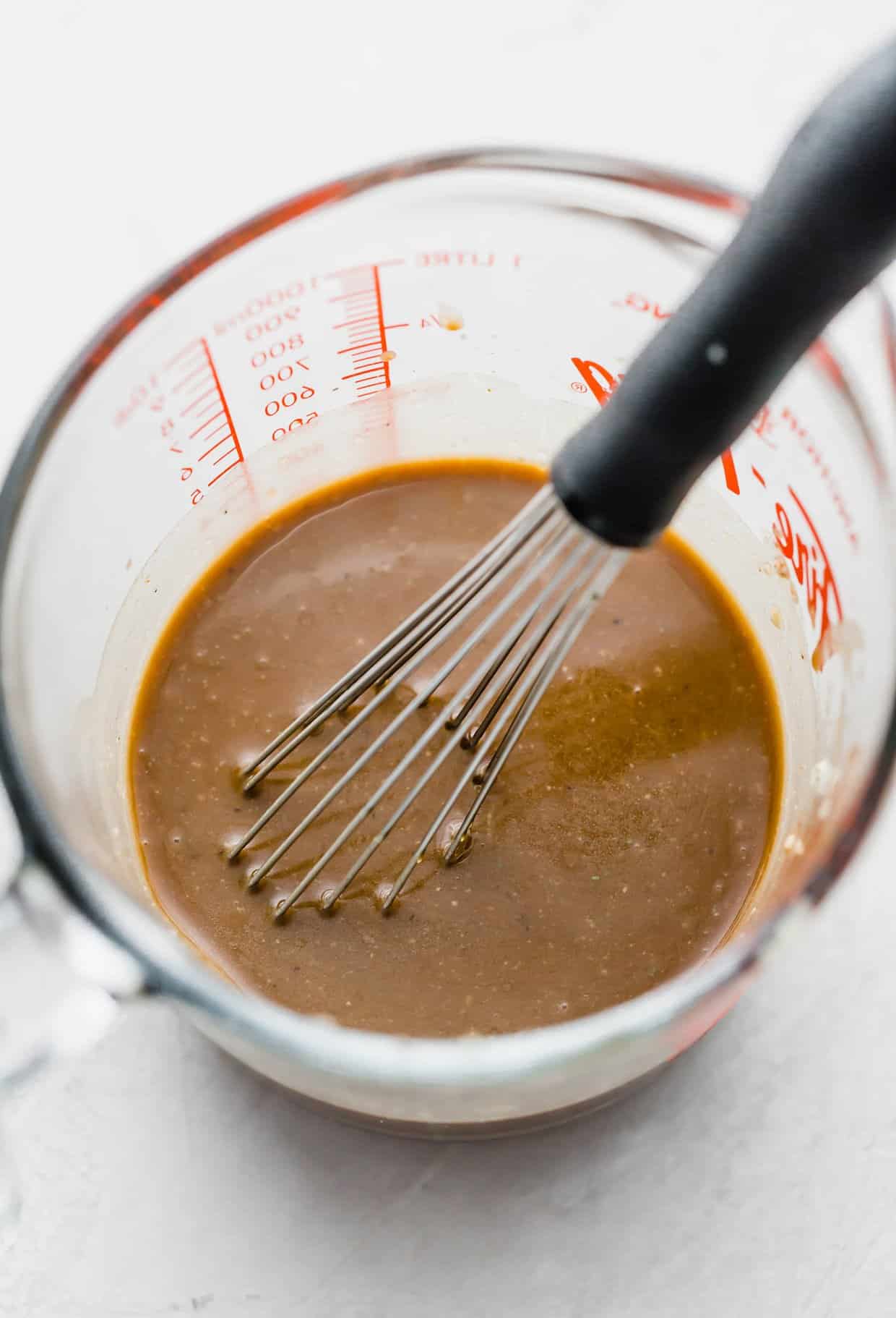 Creamy balsamic salad dressing in a glass measuring cup.