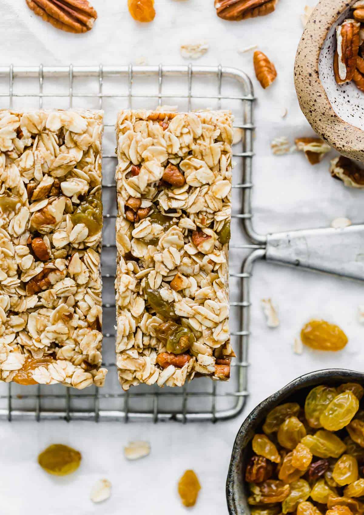 Oatmeal Raisin Granola Bars with pecans on a wire rack against a white background.