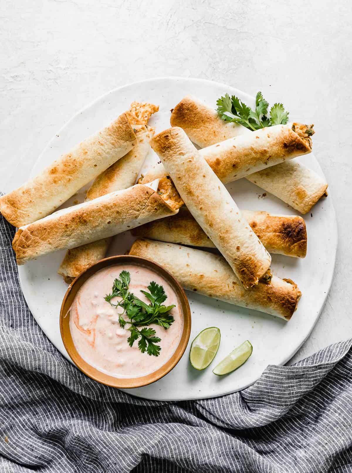 Baked Chicken Taquitos on a white plate against a white background.