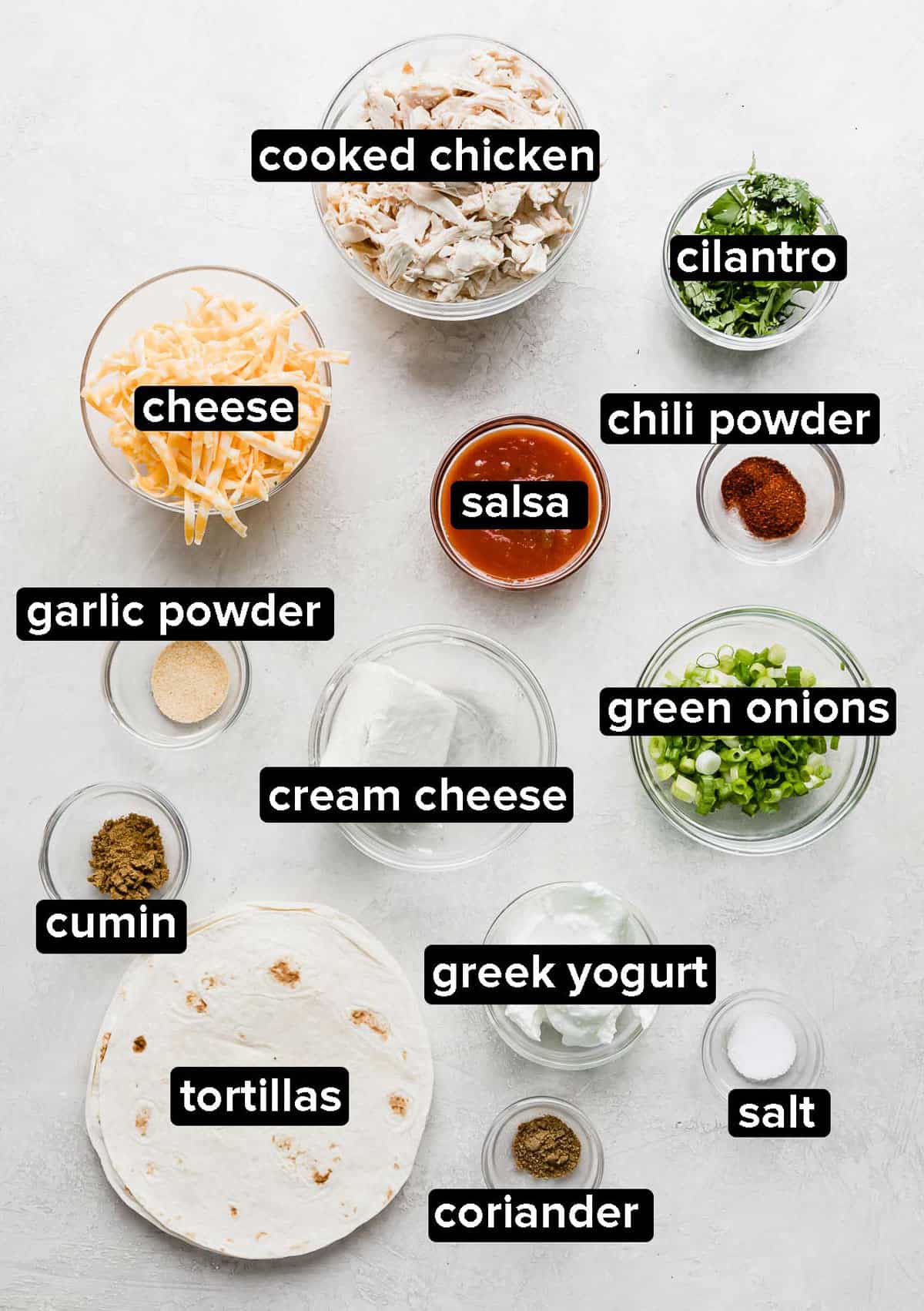 Ingredients used to make baked chicken taquitos, in glass bowls on a white background.