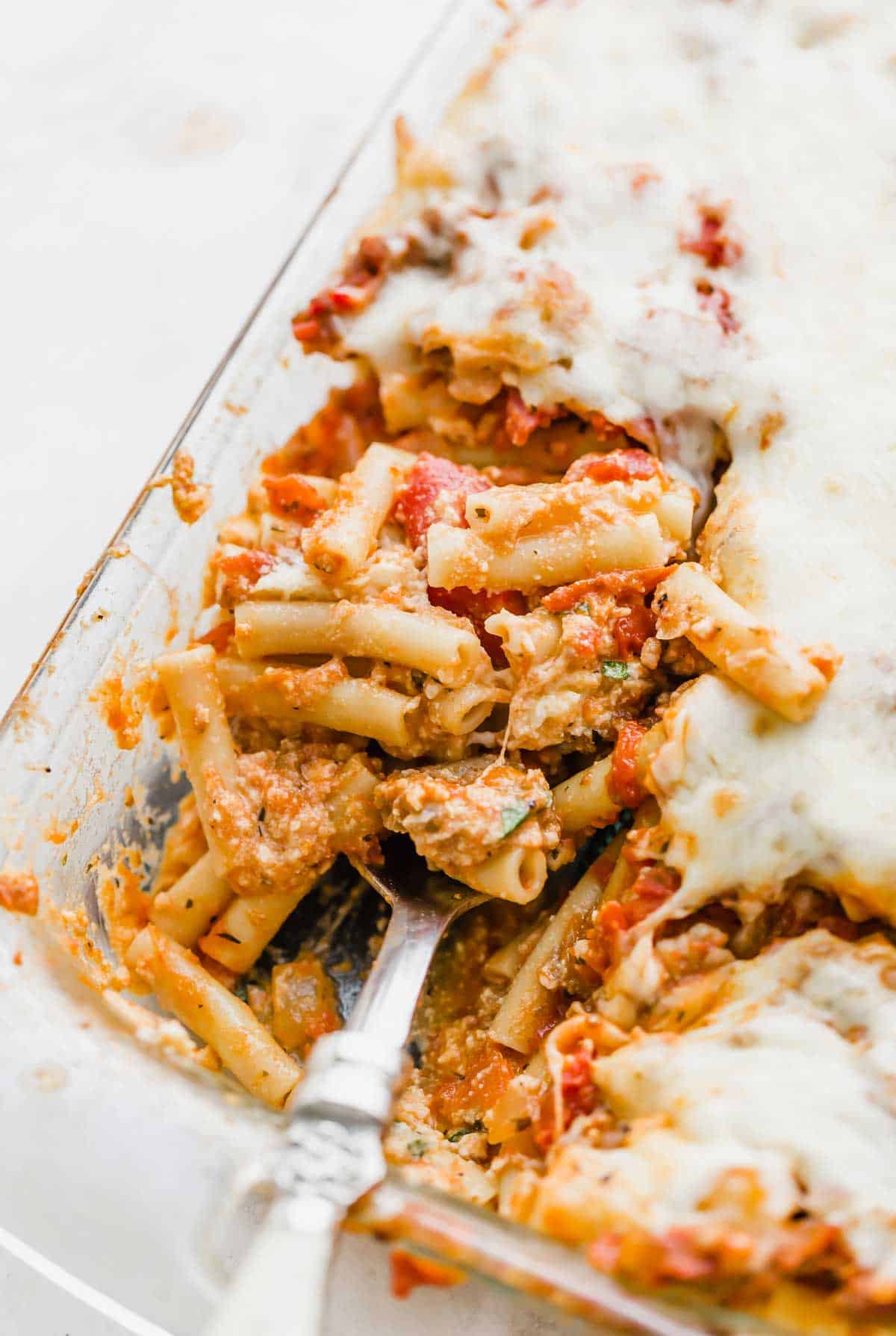 Close up image of baked ziti with ricotta cheese, in a glass pan.