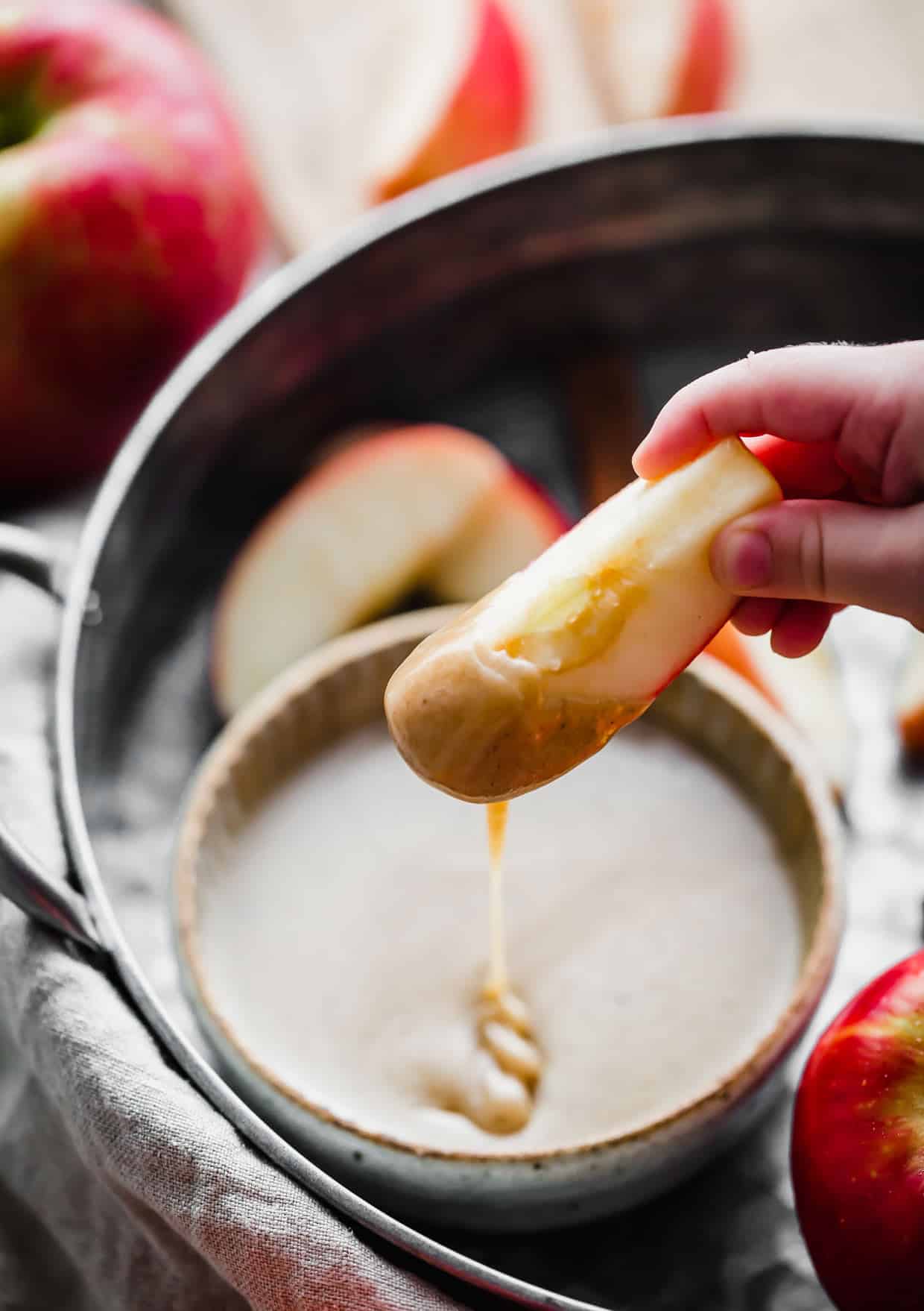 An apple slice dipped in homemade caramel dip.