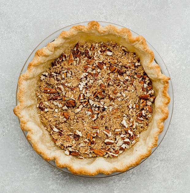 A par baked pie crust with a brown sugar and pecan filling on the bottom.