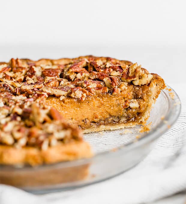 A slice of praline pumpkin pie showcasing the pecan praline at the base of the pie and on the top.